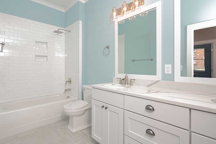 remodeled bathroom with white tile and cabinets